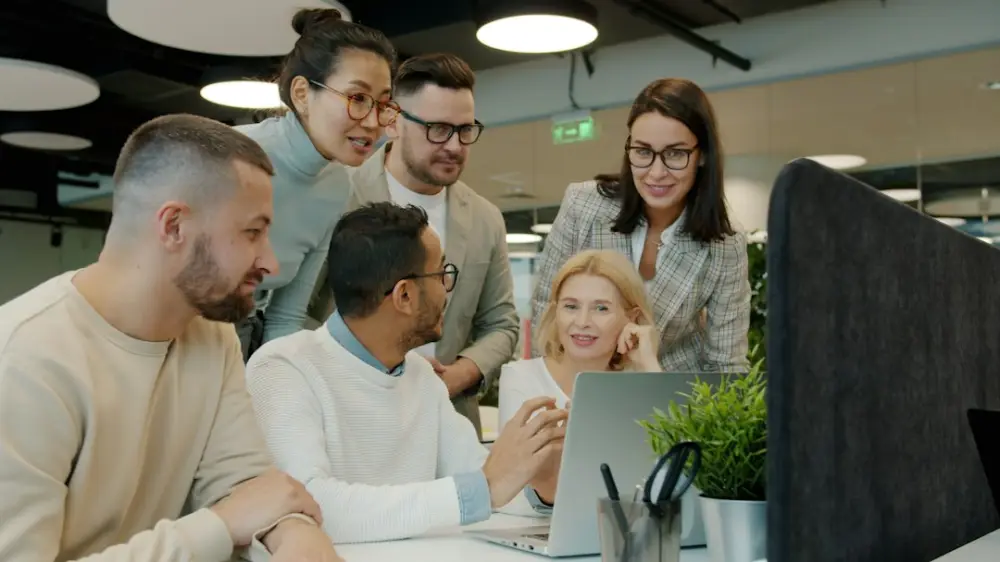 Diverse team collaborating around a laptop in office, illustrating open-source governance and maintainership